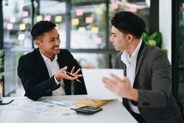 Two business men meeting to talking or discuss marketing work in workplace using paperwork, calculator, computer to work.