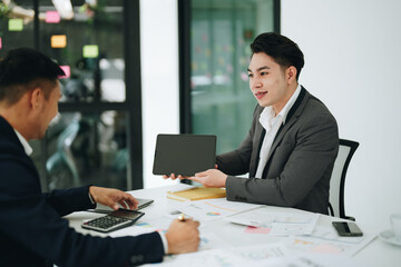 Two business men meeting to talking or discuss marketing work in workplace using paperwork, calculator, computer to work.