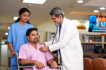 Fototapeta premium Indian male doctor checkup to patient with stethoscope on wheel chair.