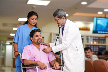 Obraz premium Indian male doctor checkup to patient with stethoscope on wheel chair.
