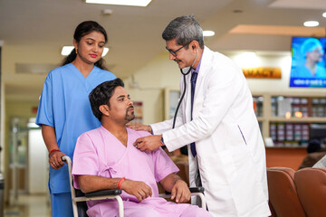 Obraz premium Indian male doctor checkup to patient with stethoscope on wheel chair.