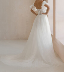 Fototapeta premium Gorgeous long wedding backless dress decorated with floral lace. Bride in the shoulderless white wedding dress with and fancy sleeves
