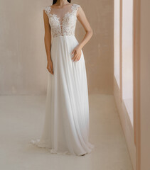 Front view of beautiful bride in the white wedding dress with deep neckline. Gorgeous sleeveless wedding dress decorated with lace