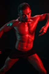 Fototapeta na wymiar Man bodybuilder posing muscles with nude fitness torso, isolated on black background in neon light. Advertising, sports, active lifestyle, colored light, competition, challenge concept. 