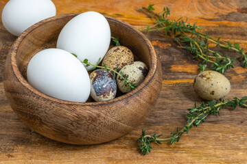 Easter eggs on wooden background. Chicken and quail eggs in wooden bowl.