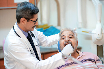 Dentist checking senior patient teeth at clinic
