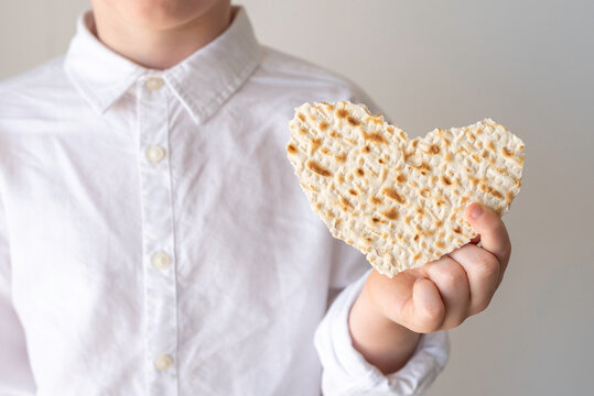 Matzah in the form of heart for Jewish holiday Pesach in the hands of a child.
