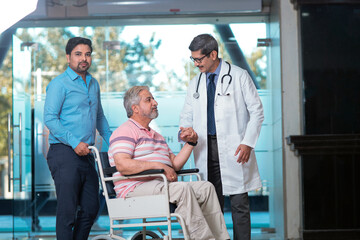 Doctors giving support to sick old man in a wheel chair