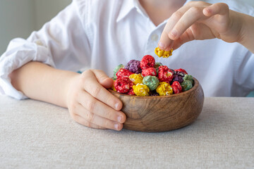 Bowl of rainbow popcorn in the hands of a child. Kid's snack.