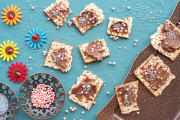 Pieces of matzah covered with chocolate paste and colorful sprinkles for Jewish holiday Pesach.