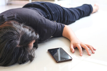 Woman fainted on the floor at home, phone fallen near her hand. 