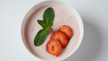 Strawberry yogurt with mint and fresh berries in white bowl