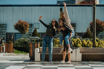 Curly haired girl taking a selfie with her brunette female friends. Smiley brunette girl giving...