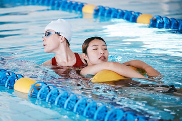 Swimming pool rescue, or woman with lifeguard for help in emergency, drowning accident or dangerous event. Fitness safety, healthcare or person saving life of Asian girl swimmer or victim in water