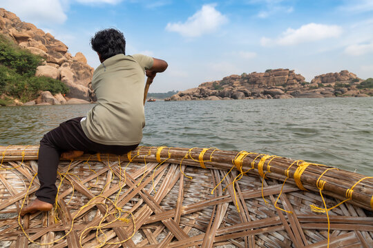 Young local boy rows a coracle boat on the Tungabhadra river at Hampi, Karnataka India