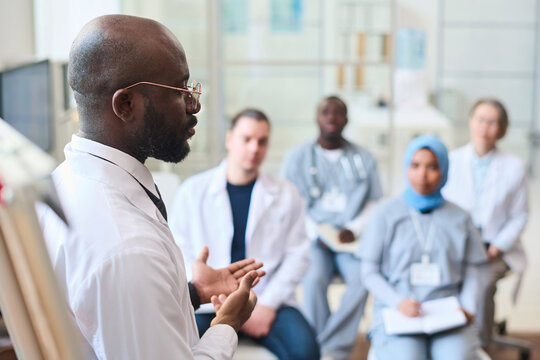 African American speaker talking to group of doctors during conference