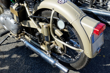 Rear wheel and chromed exhaust pipe of a classic english motorcycle . Side view