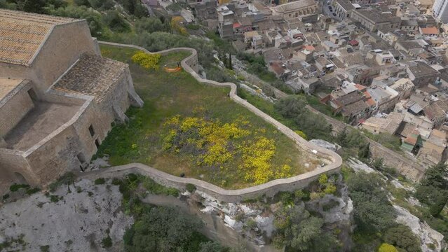 overhead view of complex of Santa Maria della Croce flying backwards revealing Sicilian town of Scicli