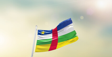 Waving Flag of Central African Republic on blur sky. The symbol of the state on wavy cotton fabric.