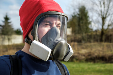 Man gardener portrait in protective full face respirator mask with dust filters. Protection from poisons and toxic air elements. PPE. Safety precautions. Equipment for pest control. Nature background