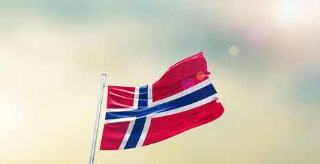 Waving Flag of Norway on blur sky. The symbol of the state on wavy cotton fabric.