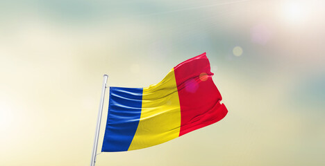 Waving Flag of Romania on blur sky. The symbol of the state on wavy cotton fabric.