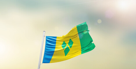 Waving Flag of Saint Vincent and the Grenadines on blur sky. The symbol of the state on wavy cotton fabric.