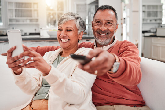 Watching Tv, Phone And Happy Couple In Home Living Room, Bonding And Having Fun. Cellphone, Television And Elderly Man And Woman Enjoying Retirement, Smile And Streaming Movie, Video Or Film On Sofa.