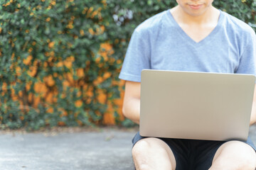 Business man in casual clothes is using laptop to check his business, work and social media in playground, outdoor garden when quarantine to work from home. Authentic business work from home concept.