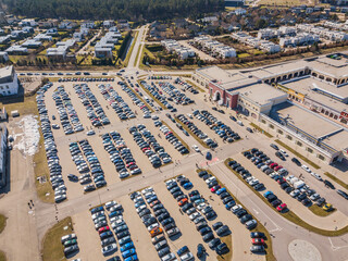 Aerial photo of full parking of many colorful cars next to a shopping centre, mall, outlet