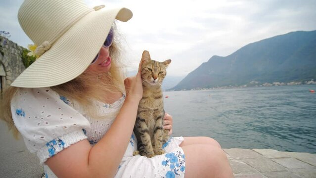 Travel with pets concept. Woman resting outdoor in the nature and play with cat