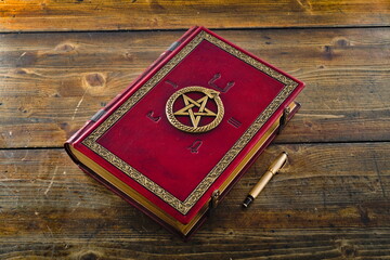 Red leather book with Ouroboros, pentagram and ancient Egyptian Symbols, lay down to wooden table