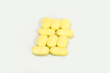 Close up shots of medicine tablets and capsules on white background. White and colored tablets placed in a group.