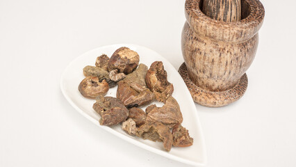 Triphala ayurvedic medicinal plant comprise of chebulic myrobalan fruit on white background with wood mortar and pestle