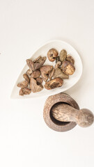 Triphala ayurvedic medicinal plant comprise of chebulic myrobalan fruit on white background with wood mortar and pestle