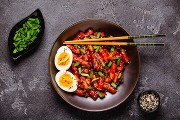Tteokbokki, Teopokki fried rice cake in black bowl.