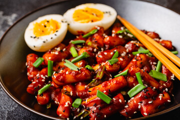 Tteokbokki, Teopokki fried rice cake in black bowl.