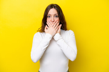 Young caucasian woman isolated on yellow background covering mouth with hands