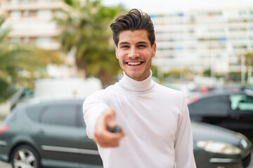 Young caucasian man at outdoors holding car keys with happy expression