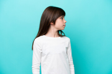 Little caucasian girl isolated on blue background looking to the side