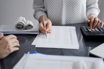 Woman accountant using a calculator and laptop computer while counting taxes for a client. Business...