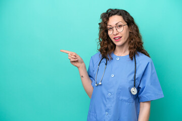 Young nurse caucasian woman isolated on blue background pointing finger to the side