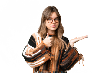 Young girl over isolated chroma key background holding copyspace imaginary on the palm to insert an ad and with thumbs up