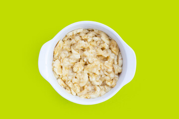 Mashed bananas in bowl on green background.