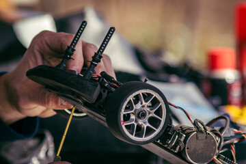 RC radio control model car chassis in electric repair, a man uses a screwdriver tool to fix the motor engine in his automobile.	