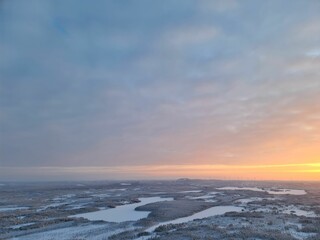 Scenic drone shot of sunset over lakes and snow-covered forests