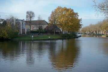 Fototapeta premium Lovely view of the Oostsingel Canal in Delft with colorful trees and houses reflected in the water