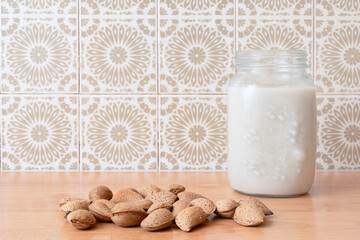 Almond milk in a glass jar with almonds on wooden table