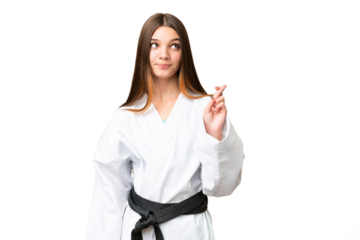 Teenager girl doing karate over isolated chroma key background with fingers crossing and wishing the best