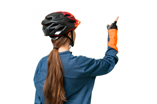 Teenager cyclist girl over isolated chroma key background pointing back with the index finger